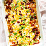 Baked enchiladas with toppings in baking dish viewed from above