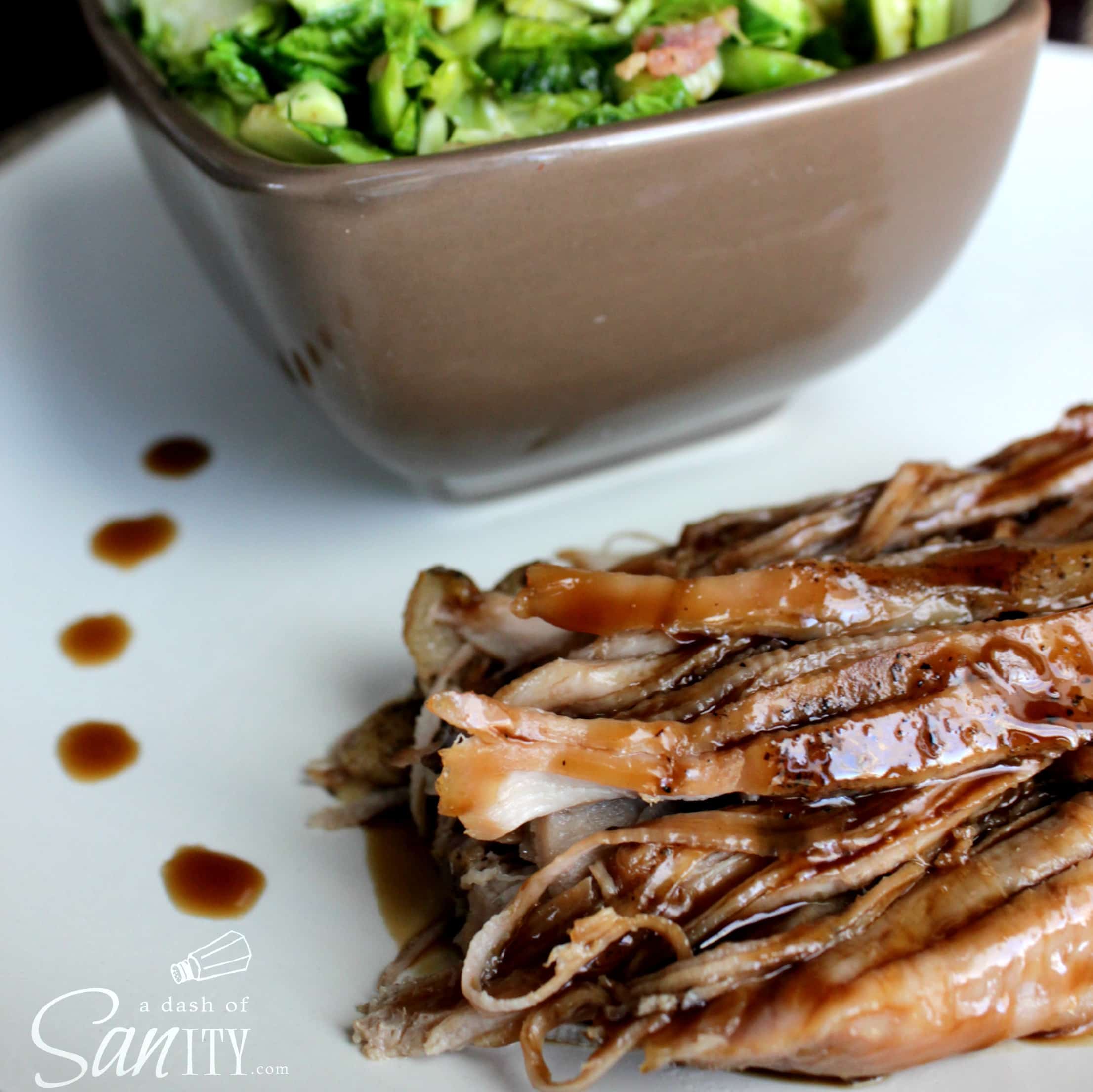 Brown Sugar and Balsamic Glazed Pork Loin served on a plate with a bowl of greens