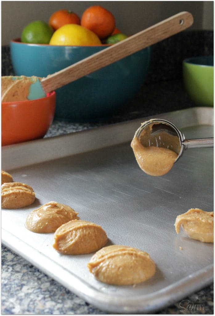 photo of cookie scoop dropping peanut butter mixture on a sheet pan