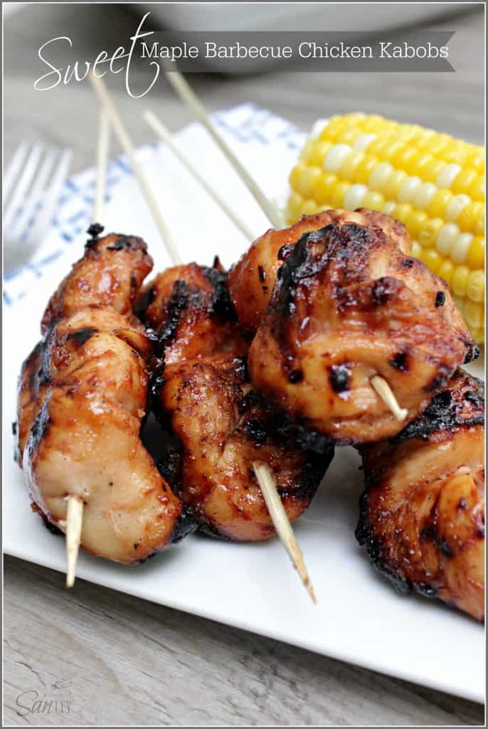 chicken kabobs on a plate with corn on the cob.