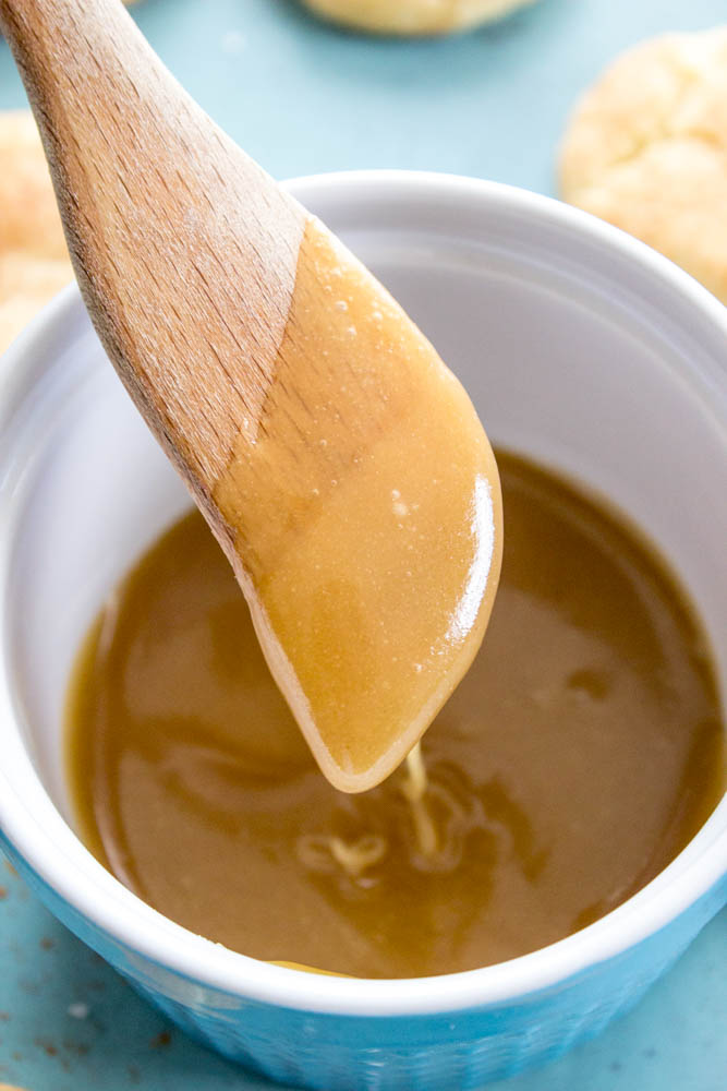 White chocolate caramel sauce in a bowl with wooden stirring spatula
