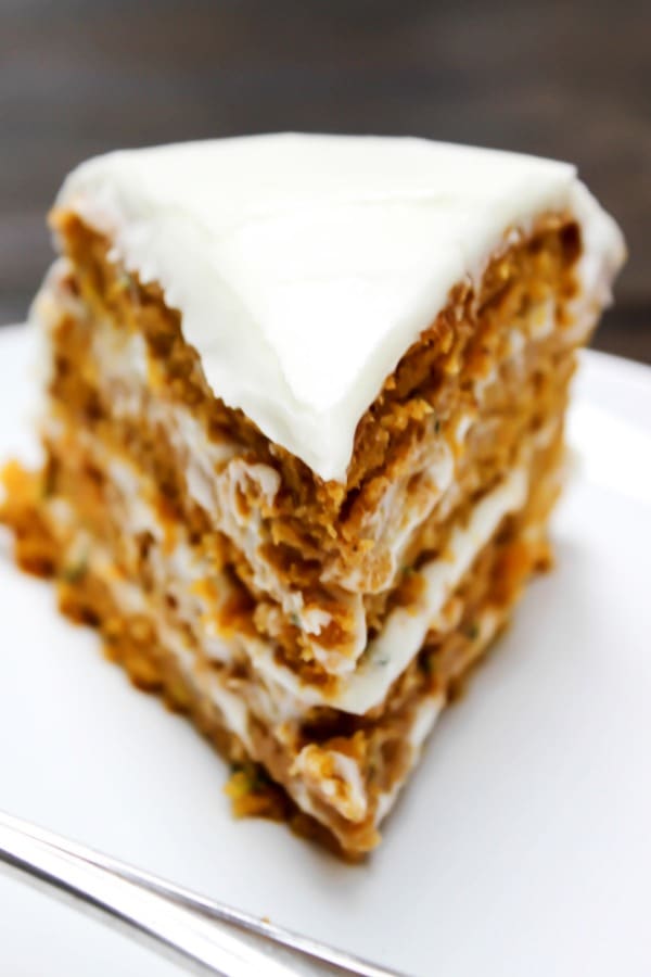 a slice of frosted zucchini pumpkin cake on a plate.