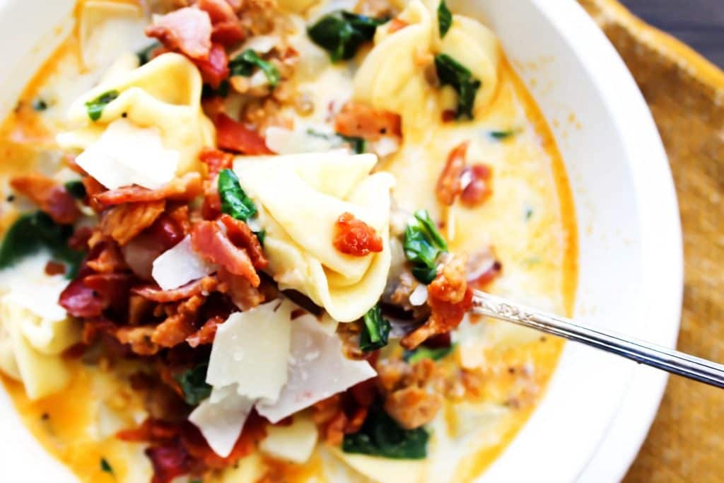 close up of Tortellini Zuppa Toscana bite on a spoon over a bowl of soup