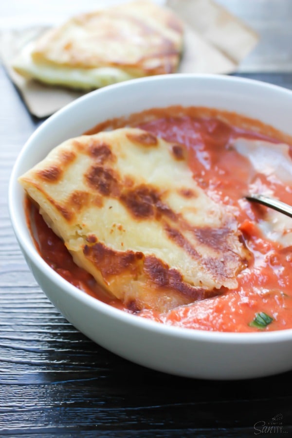 white bowl with tomato soup and crostini on top