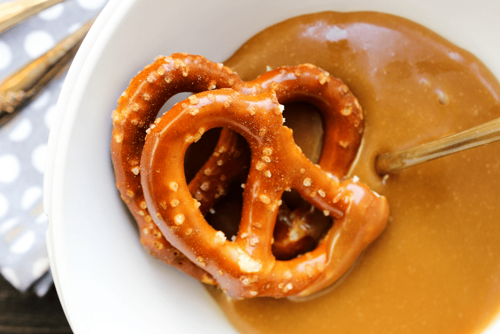 Peanut Butter Caramel Sauce in a bowl with 2 hard pretzels and a spoon