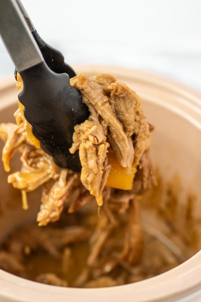 close-up photo of tongs holding shredded pork