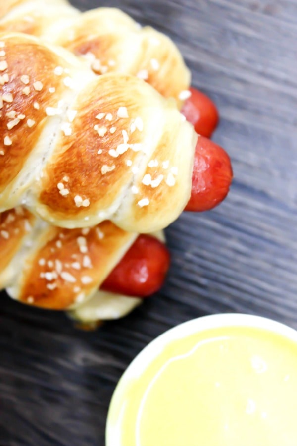 photo of a stack of pretzel hot dogs with honey mustard dipping sauce in a small bowl