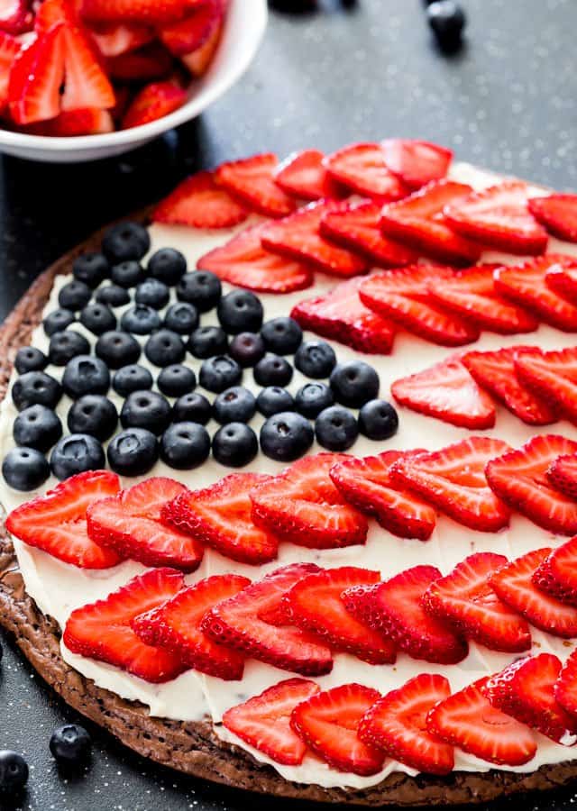 photo of a large brownie topped with frosting and fresh fruit