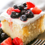 a slice of lemon poke cake topped with berries.