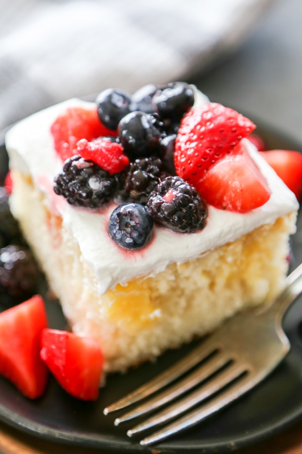 a slice of lemon poke cake topped with fresh fruit.