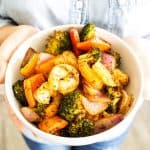 white bowl of cajun shrimp with someone holding it