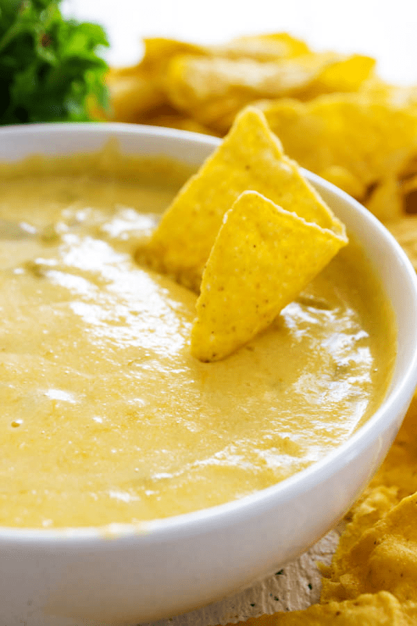 close-up shot of a tortilla chip dipped in cheese dip.