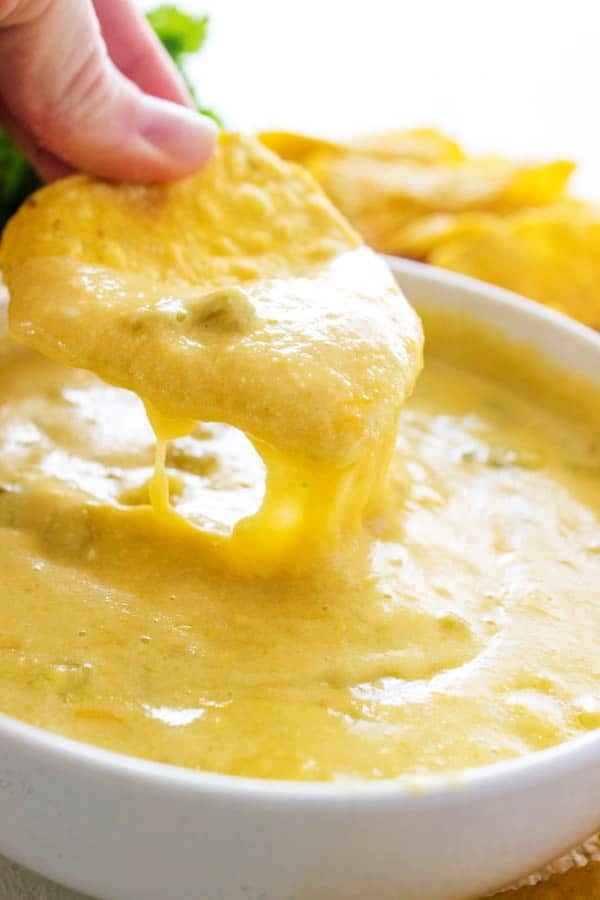 a chip being dipped in a bowl of queso