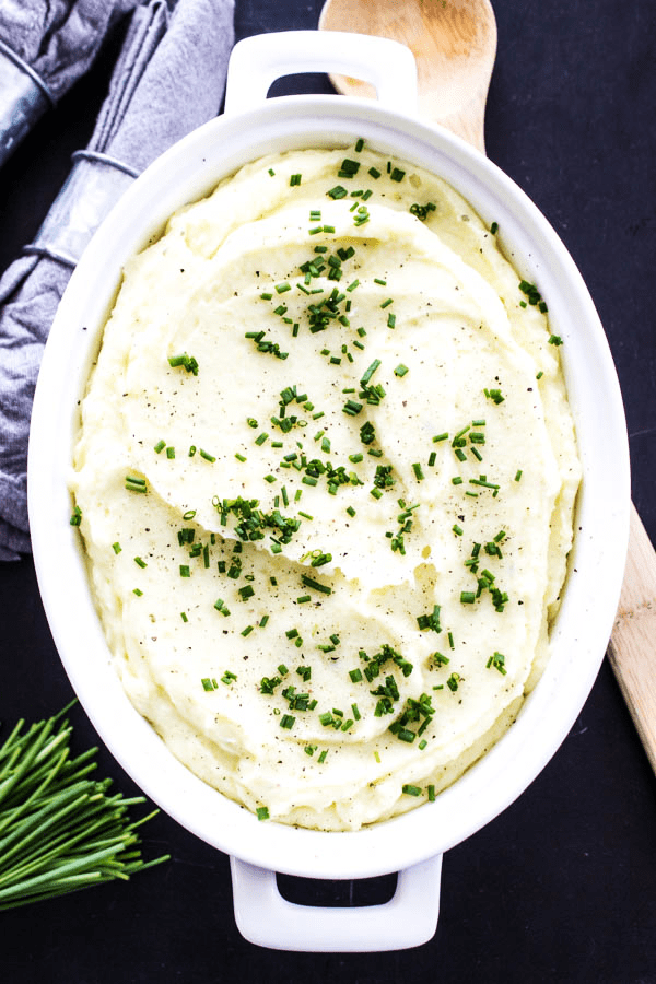 mashed potatoes topped with chopped chives in white serving dish