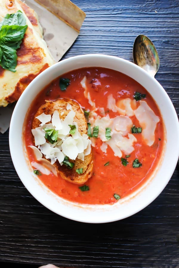 tomato basil soup in white bowl with cheese and toasted bread