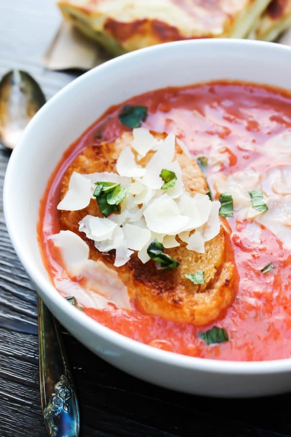 creamy tomato soup in a white bowl with bread in bowl