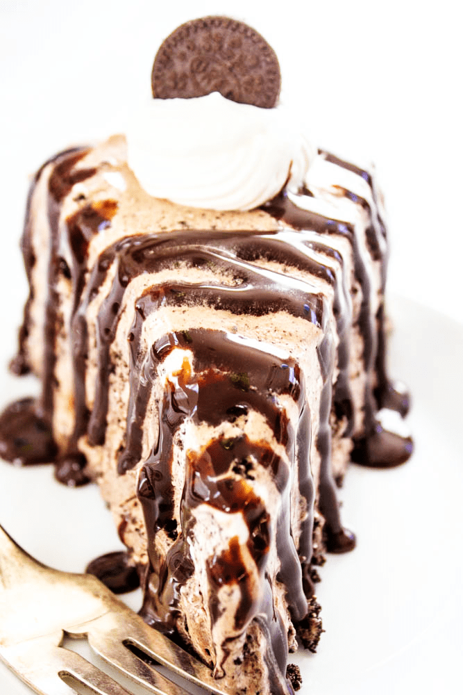 Chocolate Oreo Ice Cream Cake slice with hot fudge sauce drizzle on a plate