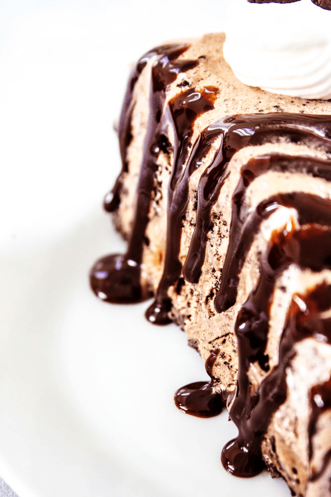 chocolate oreo ice cream cake, slice close up on a plate with hot fudge drizzle