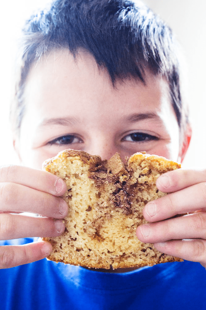 photo of boy holding slice of cinnamon sugar bread up to his face