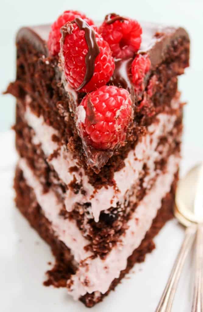 Photo of 3 layer chocolate raspberry cake slice with fresh raspberries on top