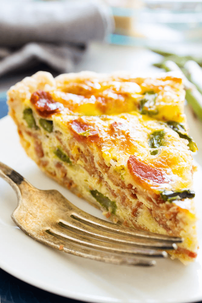 Asparagus quiche on white plate with a fork.