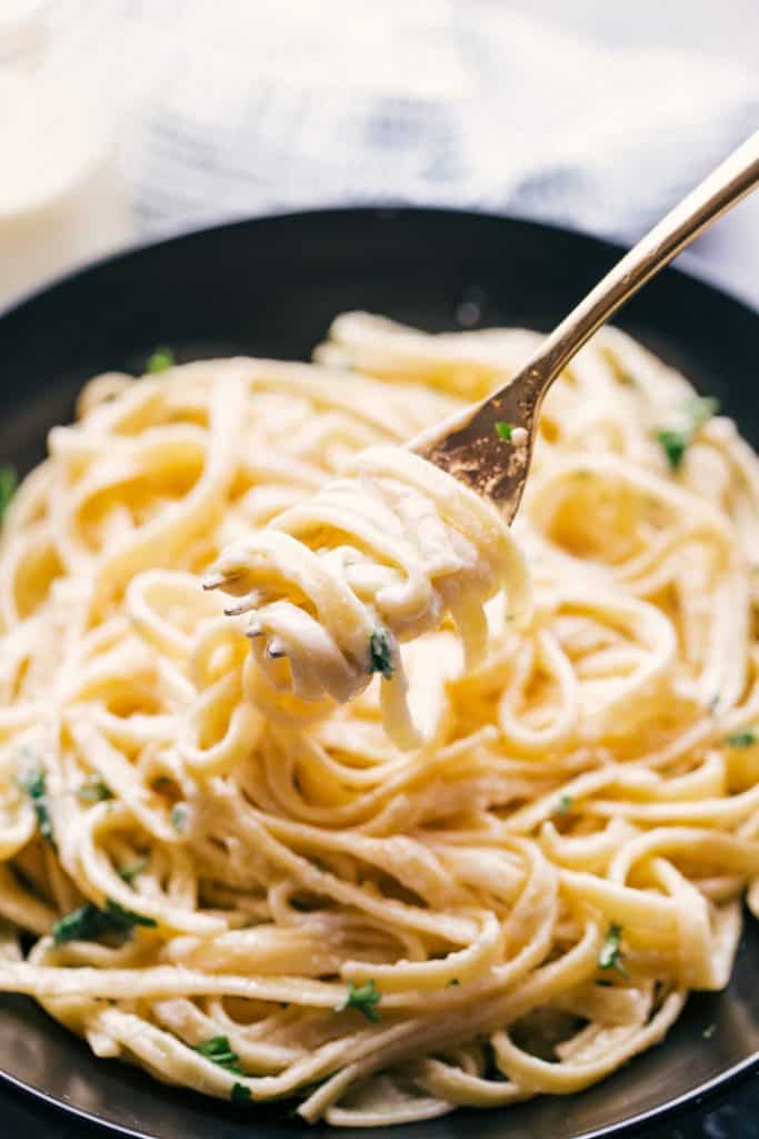 Fettuccine Alfredo served on a black plate with a fork