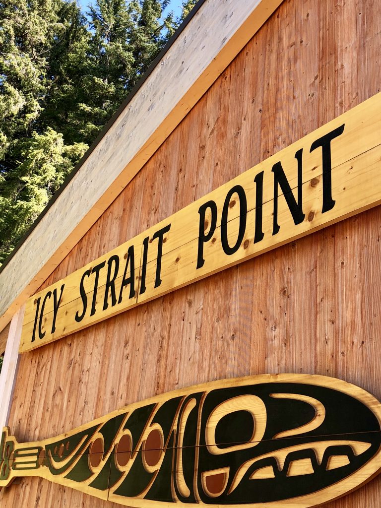 wooden building with a wooden fish carving and a sign that reads "icy strait point"