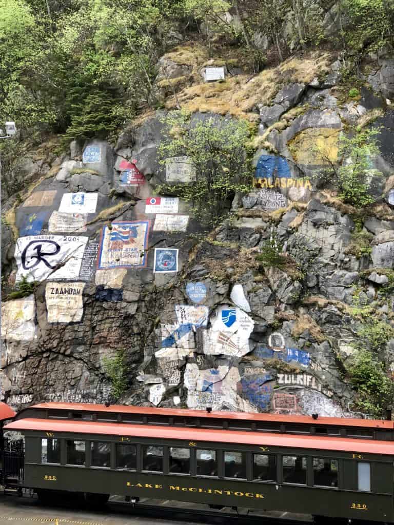 hillside with graffiti, with a train in front that says "lake mcclintock"