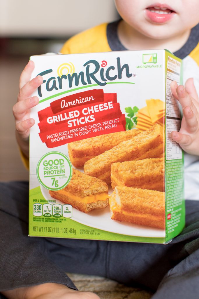 photo of a toddler holding a box of farm rich grilled cheese sticks