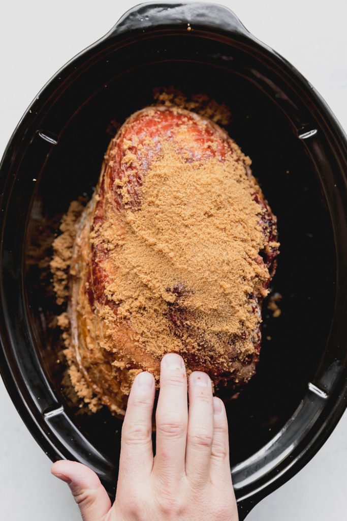 photo showing the ham in a crockpot, covered in brown sugar