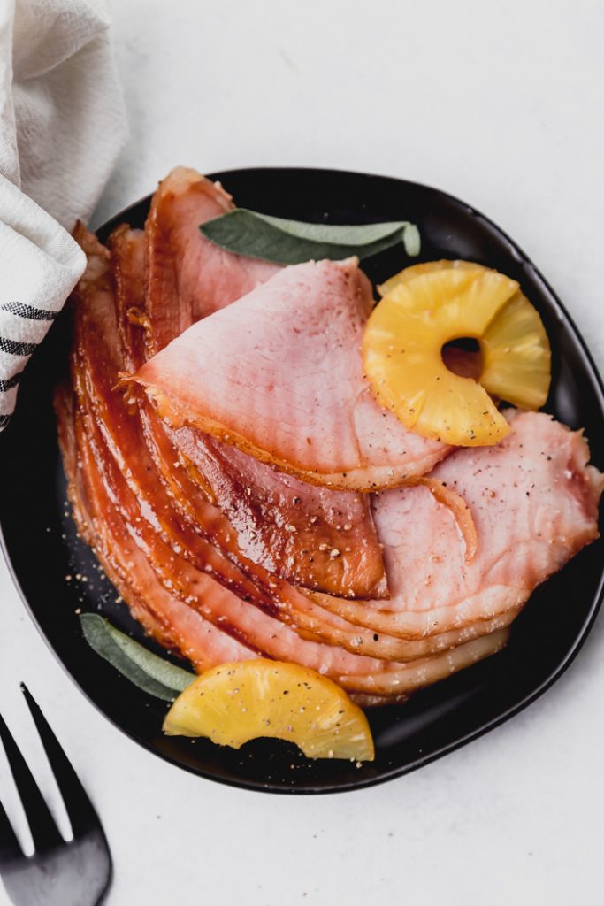 plate of crockpot ham slices with pineapple slices on a black plate