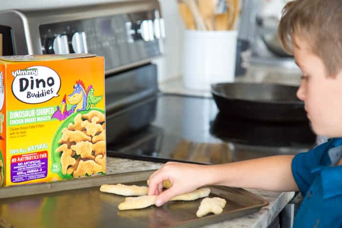 photo of a boy putting dino buddies nuggets on a sheet pan