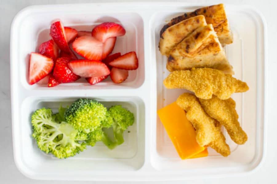 photo of lunch box with strawberries, broccoli, pita bread triangles, chicken nuggets, and cheese slices