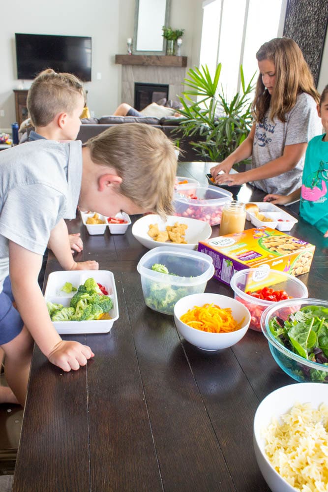 photo of kids sitting around table with bowls of prepped food, putting together their lunch boxes