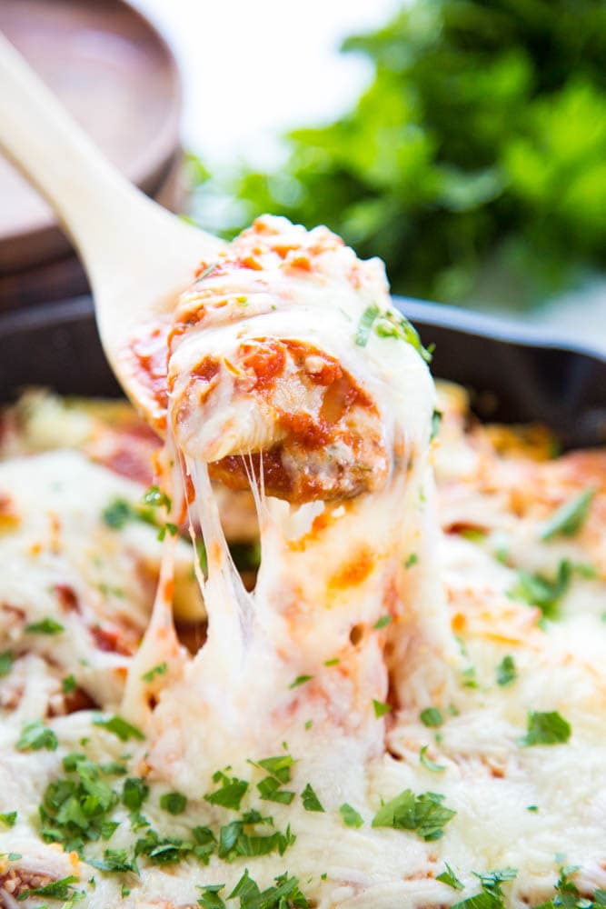 a cheesy shells being lifted out of the skillet.