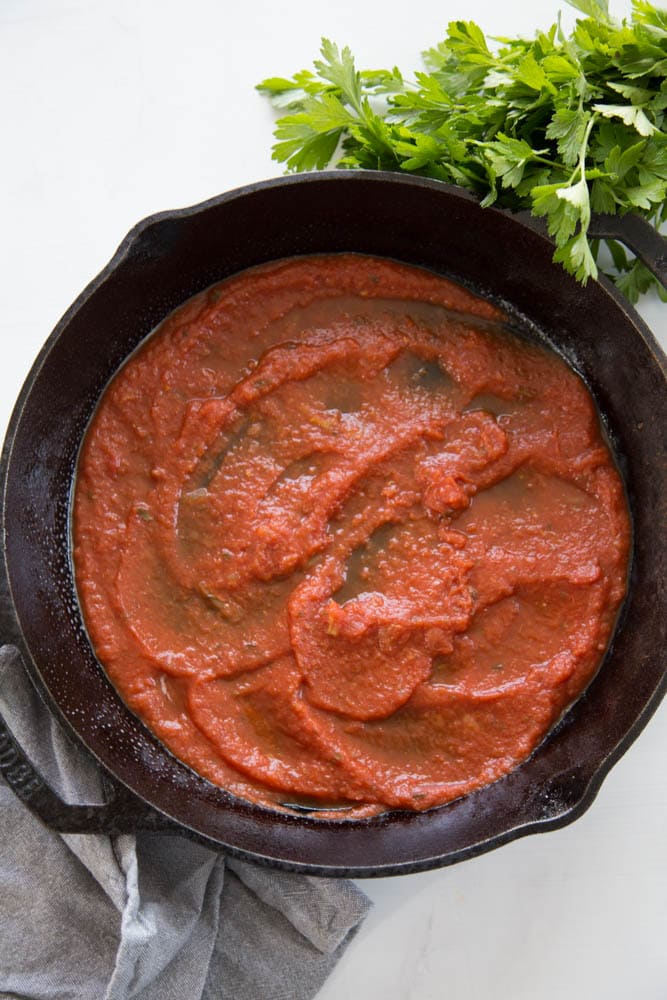 a cast iron skillet coated in marinara sauce.