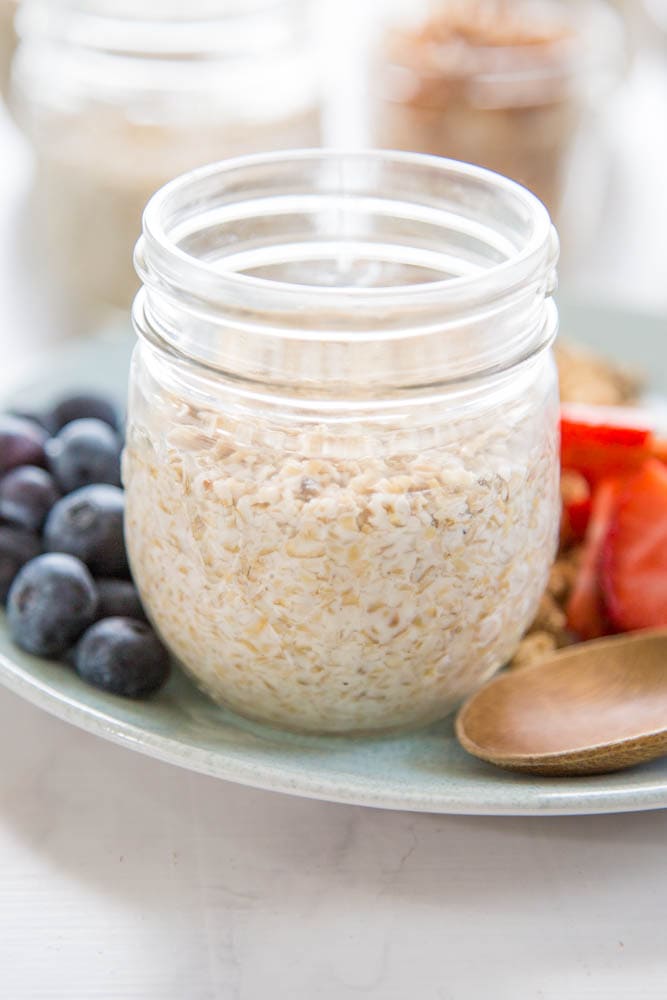 plain overnight oats in a jar on a plate with fresh fruit