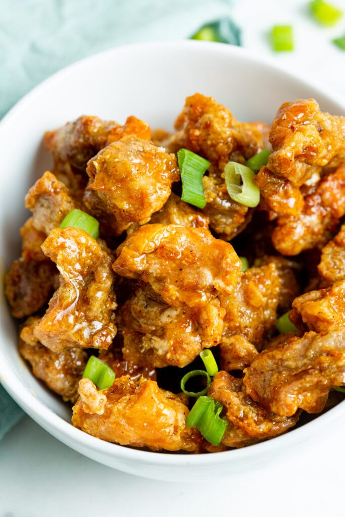 crispy honey chicken garnished with sliced green onions.