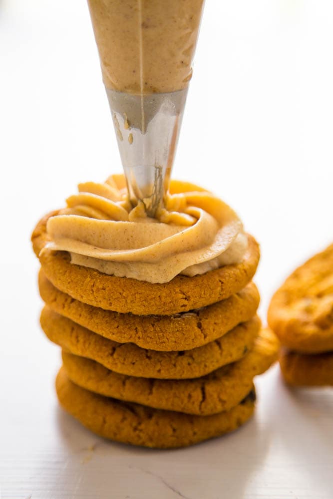 frosting being piped onto a cookie.