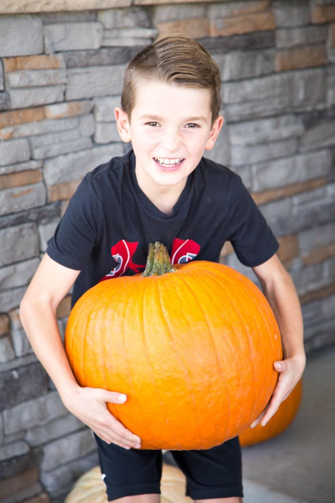 a boy holding a large pumpkin.