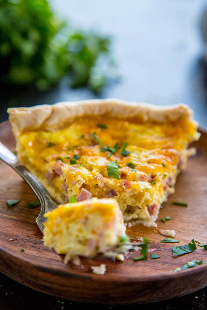 a fork with a bite of quiche with the rest of the slice