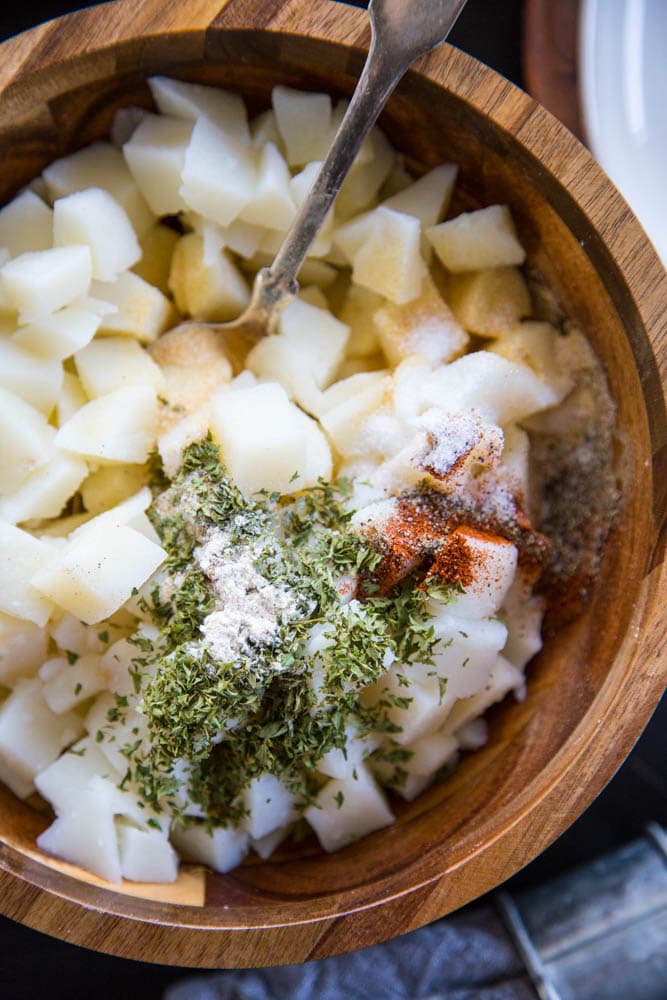 dices potatoes being mixed with the spices