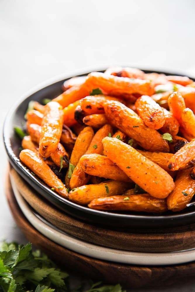 air fryer carrots on a stack of plate with fresh parsley