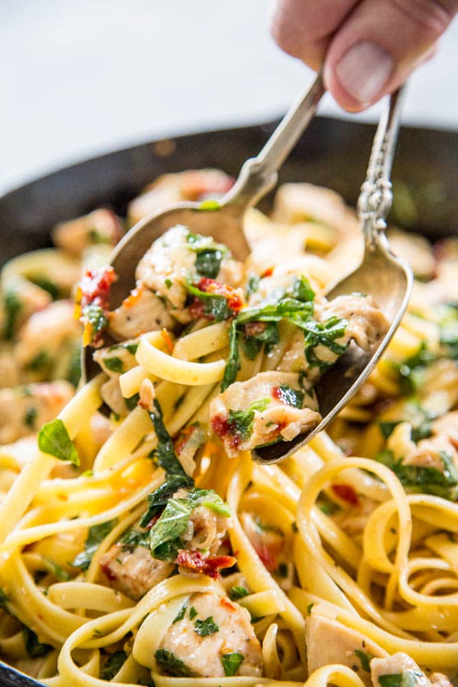 Close-up shot of pasta being lifted with two spoons.