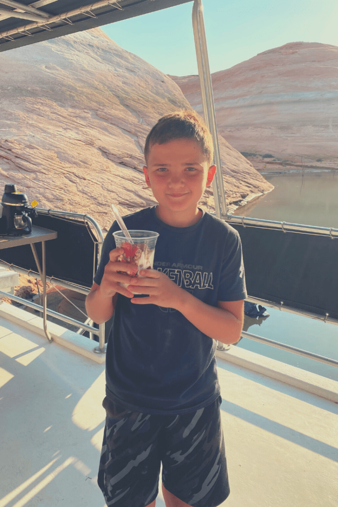 a boy on a houseboat holding a yogurt parfait.