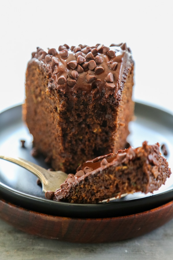 a slice of zucchini chocolate cake on a plate with a fork.