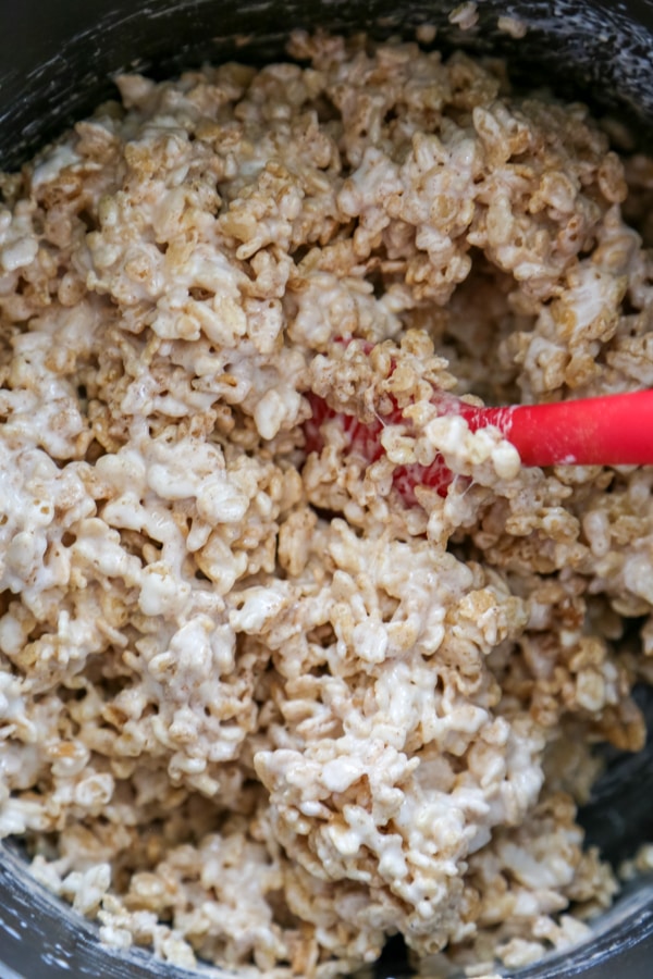 the cereal being mixed with the melted butter and marshmallows.