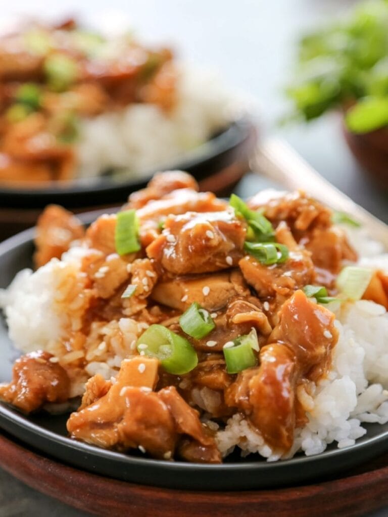 close up shot of orange chicken over rice on plate