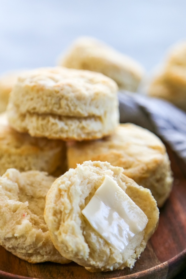 a stack of biscuits with one topped with butter.