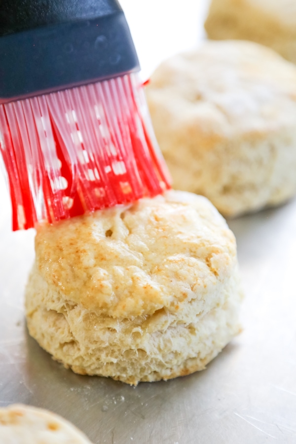 baked biscuit being brushed with butter.